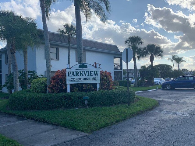 community sign with uncovered parking and a lawn