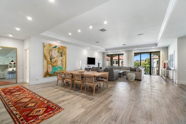 dining area with a tray ceiling, light wood-type flooring, and baseboards