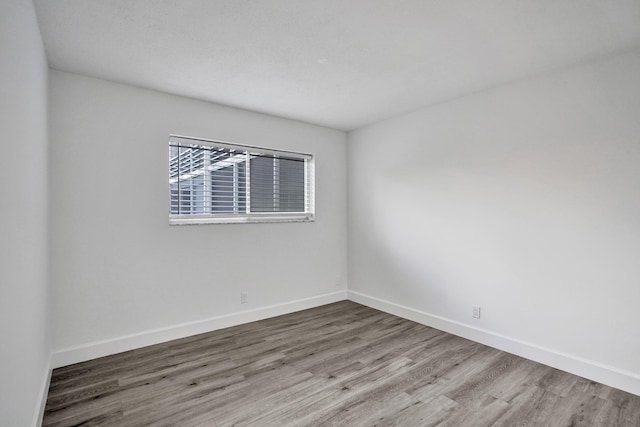 empty room featuring wood finished floors and baseboards