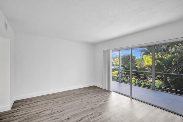 spare room with baseboards and wood finished floors