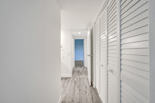 hall with light wood-style floors and baseboards