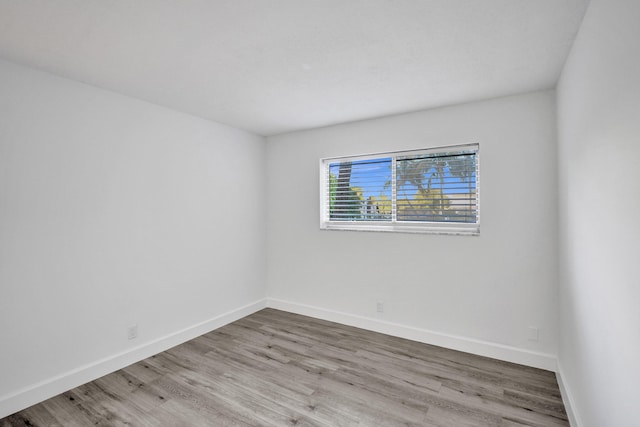 spare room with baseboards and wood finished floors