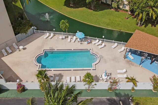 pool featuring a lawn, a patio area, fence, and a water view