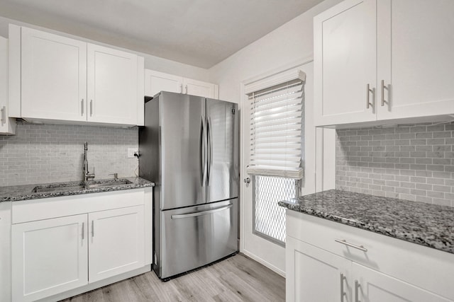 kitchen with a sink, freestanding refrigerator, and white cabinetry