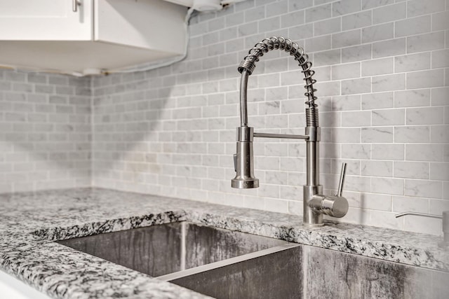 details with a sink, backsplash, and light stone countertops