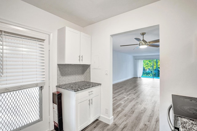 kitchen featuring tasteful backsplash, dark stone counters, white cabinets, a ceiling fan, and light wood-type flooring