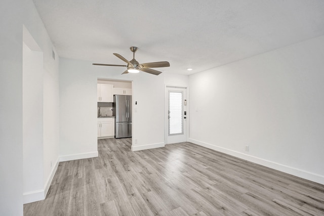 unfurnished room featuring ceiling fan, light wood-type flooring, visible vents, and baseboards