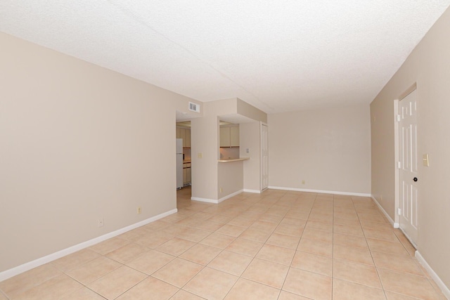 unfurnished room with a textured ceiling and light tile patterned floors