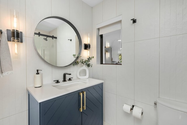 bathroom with toilet, tile walls, and vanity