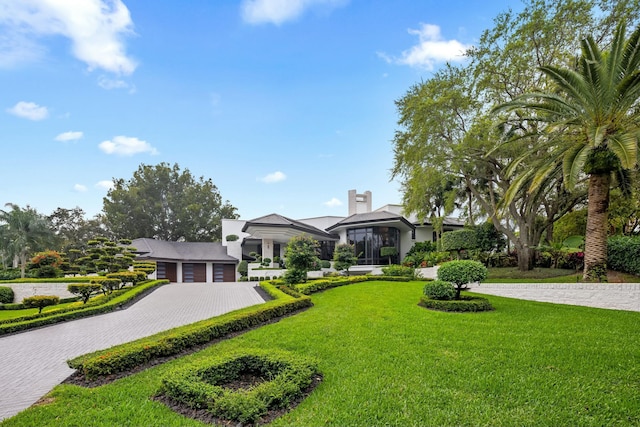 view of front of home featuring a chimney, decorative driveway, and a front yard