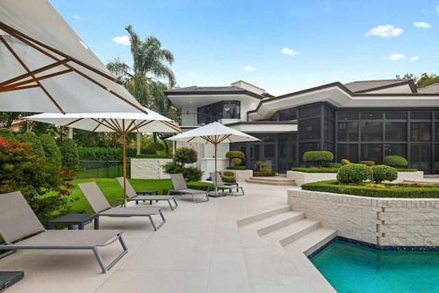 exterior space with an outdoor pool, a balcony, a sunroom, fence, and a patio area