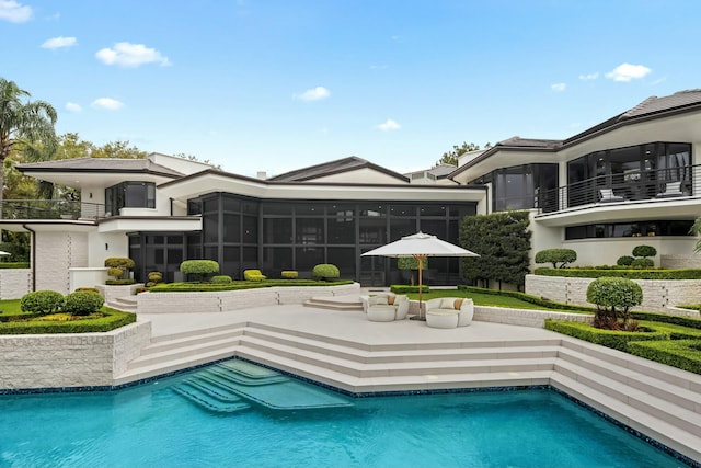 outdoor pool with a sunroom and a patio area