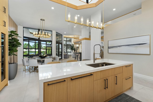 kitchen with an inviting chandelier, light countertops, modern cabinets, a sink, and light brown cabinetry
