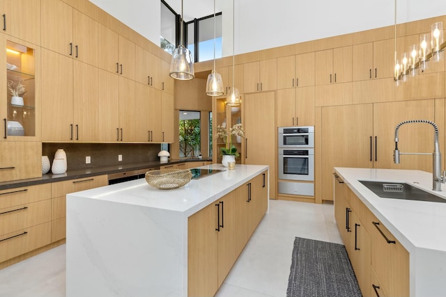 kitchen featuring a large island, light brown cabinets, stainless steel double oven, and a sink