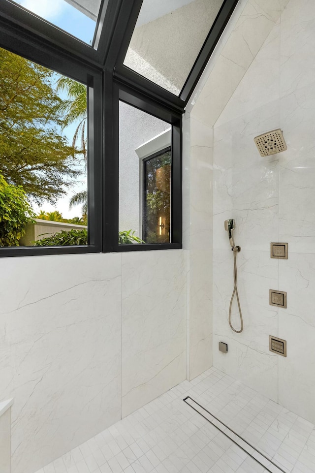 bathroom featuring a healthy amount of sunlight and a marble finish shower