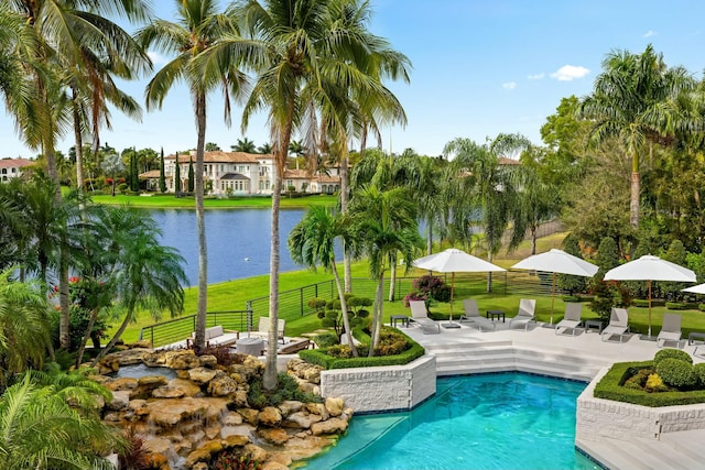 pool featuring a yard, a patio area, fence, and a water view