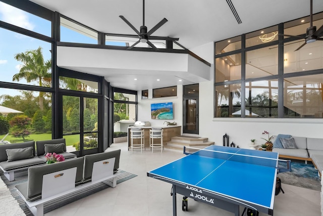 rec room with ceiling fan and a wall of windows