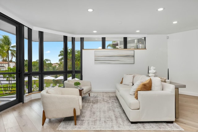 living area with baseboards, recessed lighting, wood finished floors, and floor to ceiling windows