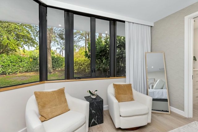 sitting room featuring wallpapered walls, wood finished floors, and baseboards