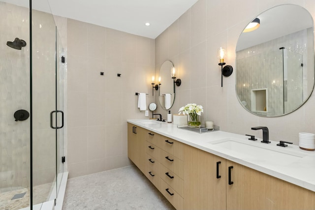 full bathroom with double vanity, tile walls, a sink, and a stall shower