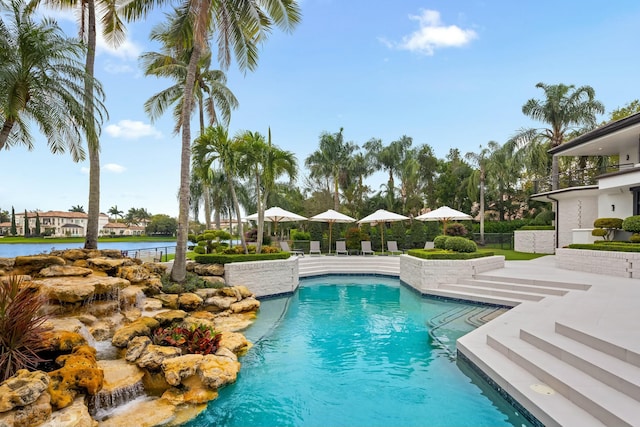 outdoor pool featuring a water view, a patio area, and fence