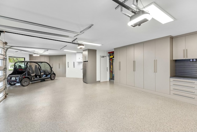 garage featuring a garage door opener and freestanding refrigerator