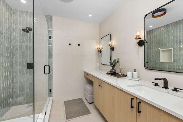 bathroom with recessed lighting, a sink, tile walls, a shower stall, and double vanity