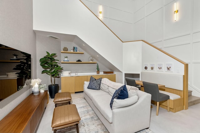 living room featuring a high ceiling, visible vents, and a decorative wall