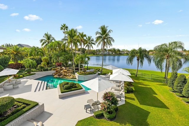 pool featuring a water view, a yard, a patio area, and fence