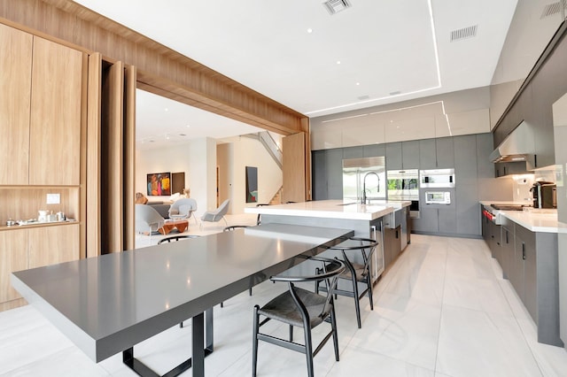 kitchen with under cabinet range hood, modern cabinets, visible vents, and light countertops