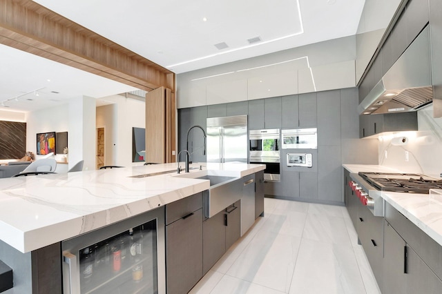 kitchen with wine cooler, ventilation hood, appliances with stainless steel finishes, modern cabinets, and a large island with sink