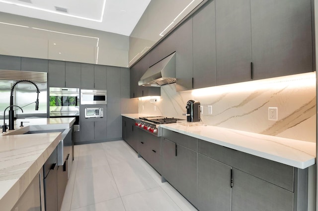 kitchen featuring stainless steel appliances, gray cabinets, extractor fan, and backsplash