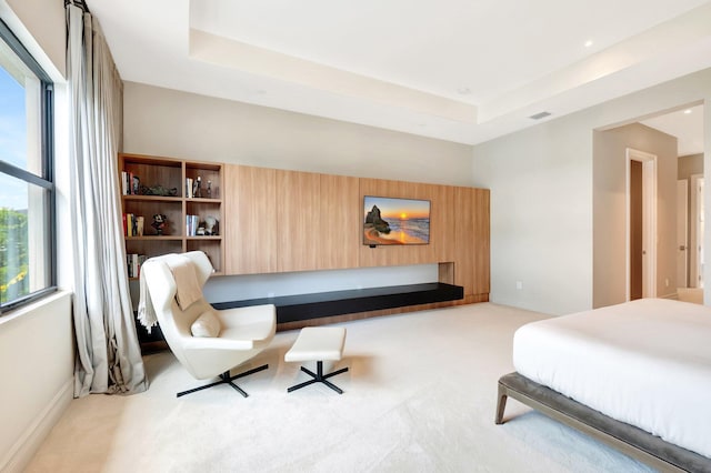 bedroom featuring a raised ceiling, light carpet, visible vents, and baseboards