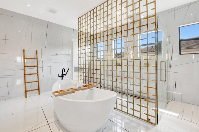 bathroom featuring a marble finish shower, a soaking tub, marble finish floor, stone wall, and tile walls