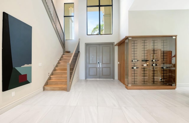 entryway with baseboards, stairs, a high ceiling, and tile patterned floors