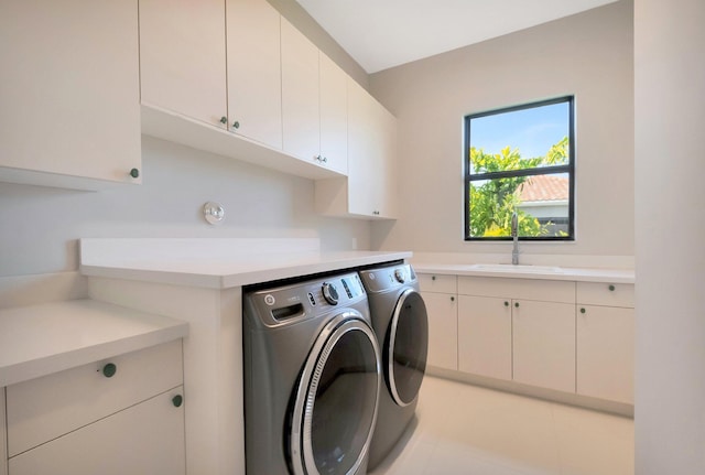 laundry area with cabinet space, separate washer and dryer, and a sink