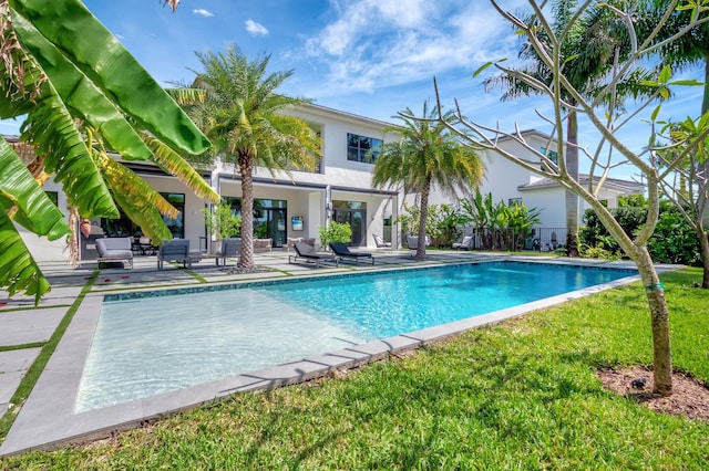 outdoor pool featuring a patio area and a lawn