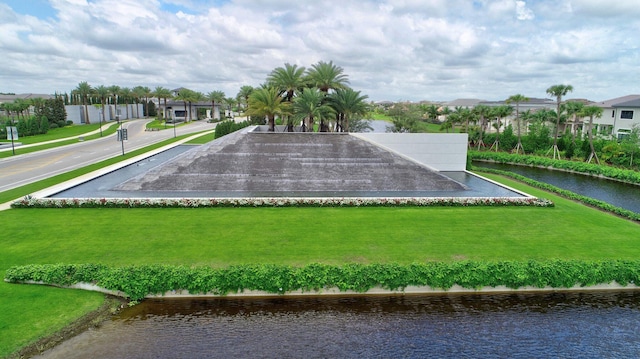 surrounding community with a water view and a yard