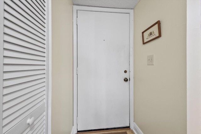 doorway to outside with baseboards and a textured ceiling