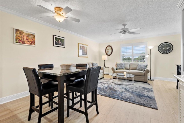 dining room with a ceiling fan, light wood-type flooring, crown molding, and a textured ceiling