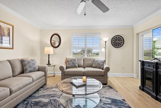 living room with a ceiling fan, a wealth of natural light, crown molding, and light wood-style flooring