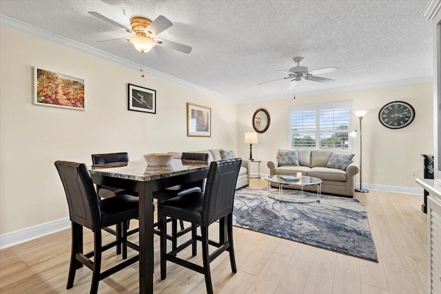 dining room with crown molding, a ceiling fan, and light wood-style flooring
