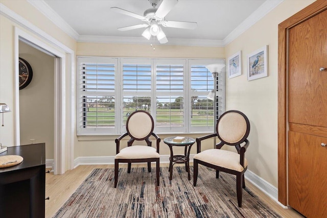 sitting room with light wood finished floors, ceiling fan, ornamental molding, and baseboards