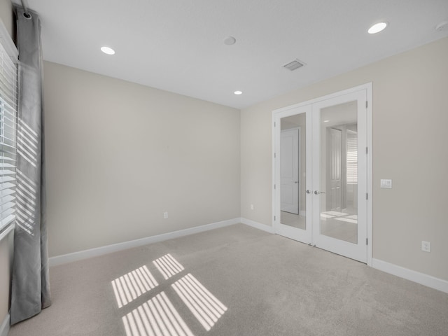 unfurnished bedroom featuring visible vents, light colored carpet, and french doors