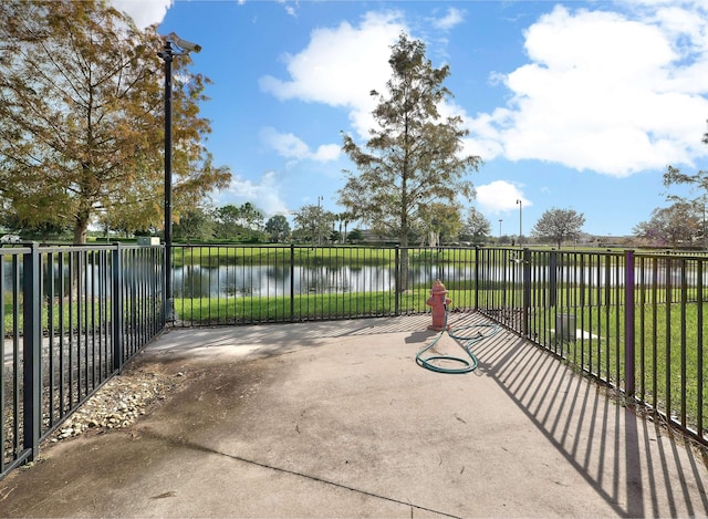 view of patio / terrace featuring a water view and fence