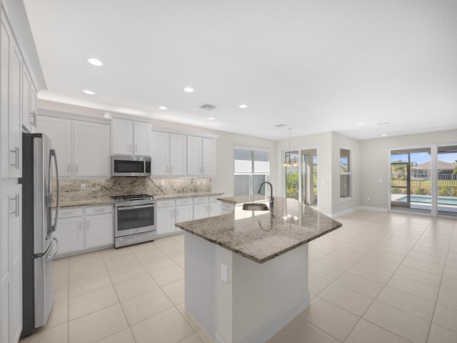 kitchen with a kitchen island with sink, appliances with stainless steel finishes, white cabinets, and a sink