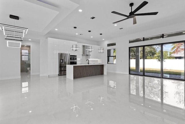 interior space featuring a center island with sink, stainless steel appliances, white cabinetry, and hanging light fixtures