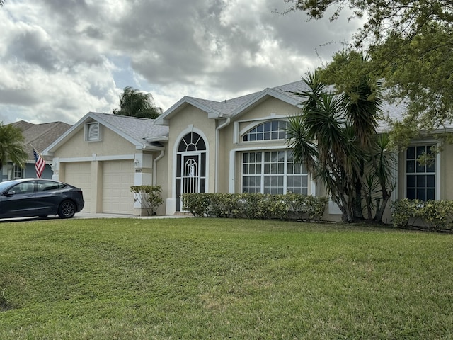 single story home with an attached garage, a front lawn, and stucco siding