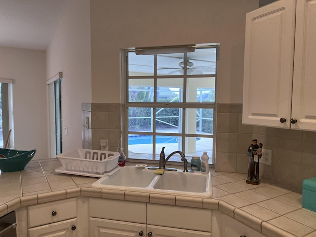 kitchen featuring a healthy amount of sunlight, white cabinetry, a sink, and ceiling fan