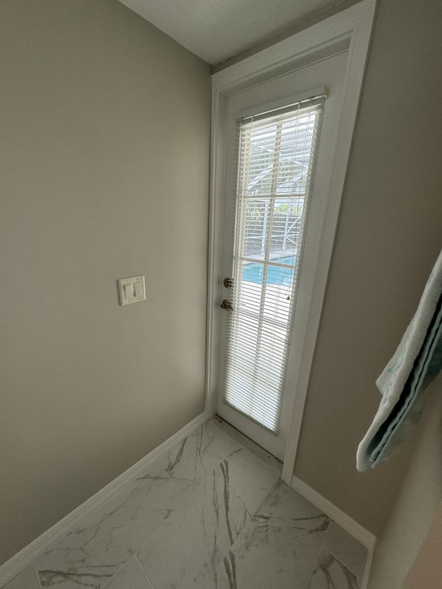 doorway with marble finish floor and baseboards